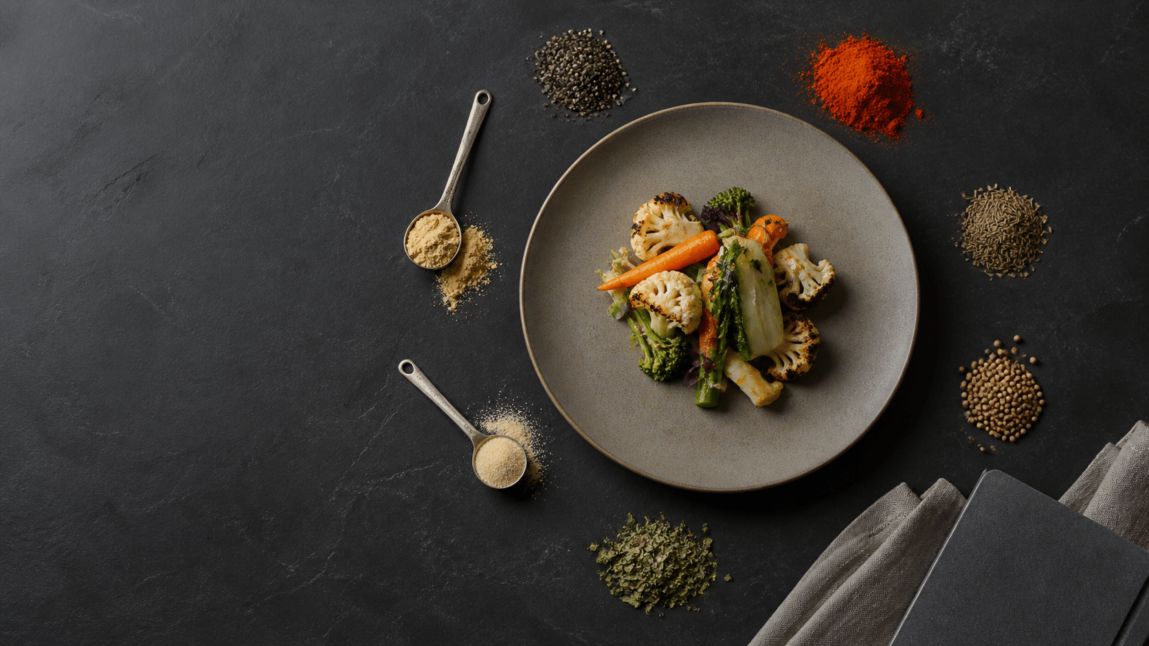 Sept épices polyvalentes disposées autour d’une assiette de légumes en vue de dessus